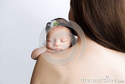 A newborn baby girl sleeps on her mother`s bare shoulder with her hand pressed to her cheek Stock Photo