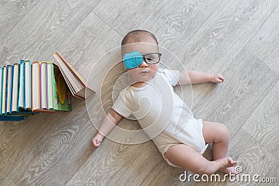 Newborn baby in glasses with books. A little boy in white clothes and blue . Beautiful portrait of a toddler. Big-eyed baby. Remot Stock Photo