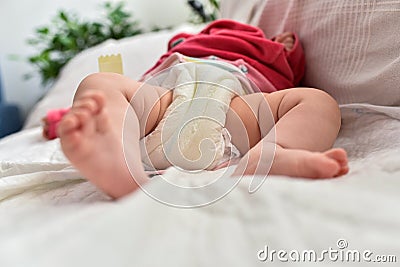 Newborn baby laying on a sofa with disposable diapers ready to change Stock Photo