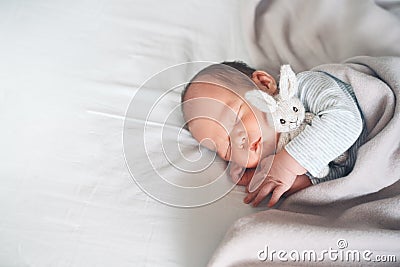 Newborn sleep at first days of life. Portrait of new born baby one week old with cute soft toy in crib in cloth background Stock Photo