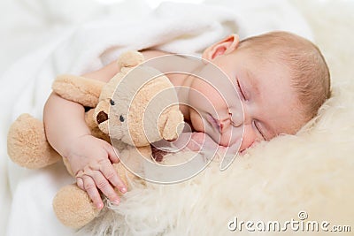 Baby with toy sleeping on fur bed Stock Photo