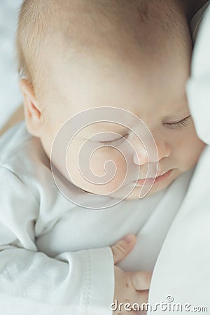 Newborn baby sleeps in the arms of a parent. portrait of infant. soft tinted Stock Photo