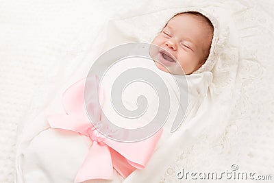 Newborn Baby Smile, New Born Girl Smiling Wrapped by Ribbon Bow Stock Photo
