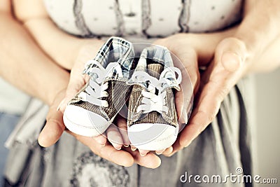 Newborn Baby Sneakers in Family Hands, Parents Holding New Born Kids Booties Stock Photo