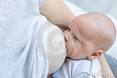 A newborn baby sucks milk from the mother`s breast and falls asleep in her arms, the concept of breastfeeding Stock Photo