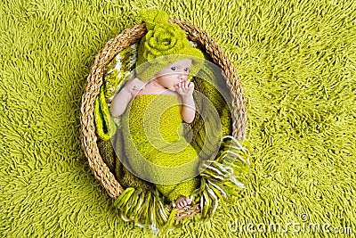 Newborn baby in woolen green hat inside basket Stock Photo