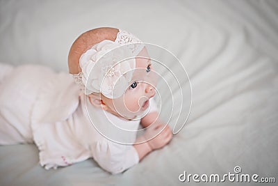 newborn baby yawns. girl lies on stomach in crib and opens mouth Stock Photo