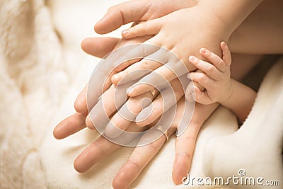 Newborn child hand. Closeup of baby hand into parents hands. Family, maternity and birth concept. Stock Photo