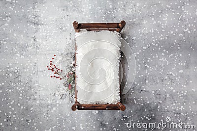 Newborn Christmas backdrop - wooden bed with white faux fur, snow covered branches with red berries on white background Stock Photo