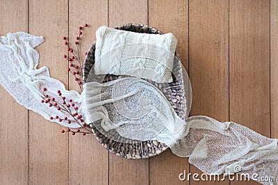 Newborn digital background - woven basket with white knitted pillow, white cheese cloth and red berries branch on wooden Stock Photo