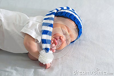 Newborn in hat on white blanket, asian baby stomach ache. Infant care, teething pain, colic ache Stock Photo