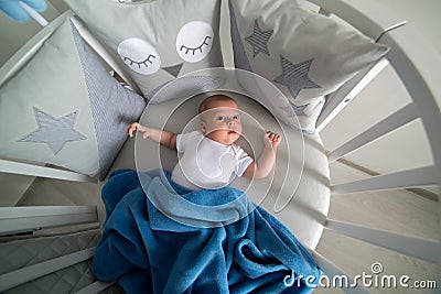 Newborn lies in the round white bed with mobile Stock Photo