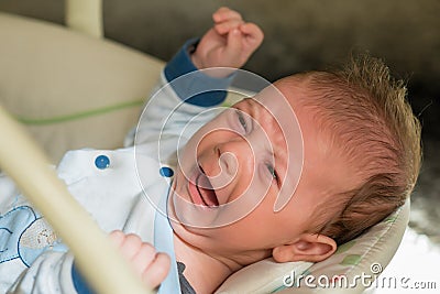 The newborn lies on swing automatic electrical chair and crying Stock Photo