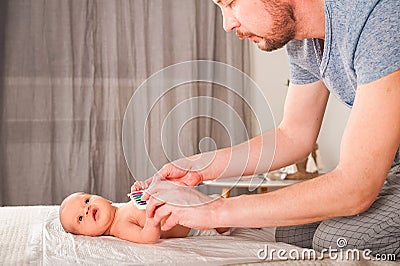 Newborn with paints on a white plaid closeup. Infant holds watercolor rainbow paint and copy space. The concept of the game, care Stock Photo