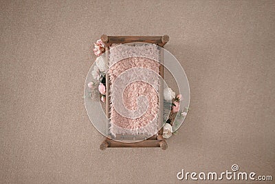 wooden bed with pink fur and floral arrangement. Newborn girl photography backdrop Stock Photo