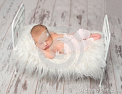 Newborn sleeping baby holding toy on cute little bed Stock Photo