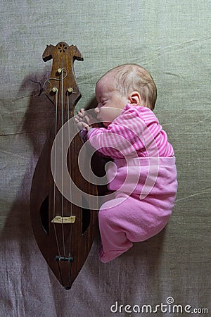 A newborn baby with a folk stringed musical instrument Stock Photo