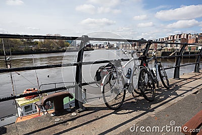 Pair of bikes leaning on a railing by river during a rest stop in the sunshine Editorial Stock Photo