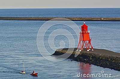 Newcastle, United Kingdom - October 5th, 2014 - Becalmed sailing dinghy in the mouth of the river Tyne is being towed ashore by a Editorial Stock Photo