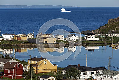 Newfoundland coastal town with distant iceberg Editorial Stock Photo