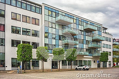 Newly build apartment building with trees and car parking lots in front of it Editorial Stock Photo