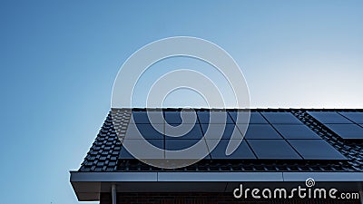 Newly build houses with solar panels attached on the roof against a sunny sky Close up of new building with black solar Stock Photo