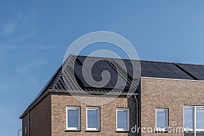 Newly build houses with solar panels attached on the roof against a sunny sky Close up of new building with black solar Stock Photo