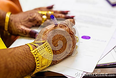 A newly married indian bengali wife with golden ornament and blacelet signing marriage registration form Stock Photo