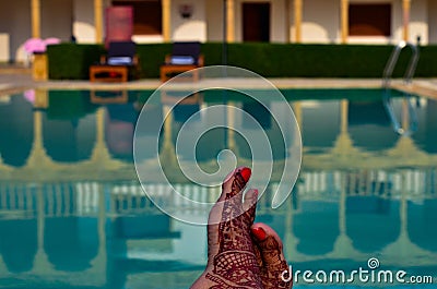 Newly married woman with henna feet in front of a swimming pool on her honeymoon in a resort in Jaisalmer, India Stock Photo