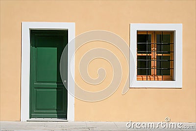 Newly restored facade of a new building consisting of a window and a green door with a yellow wall. Stock Photo