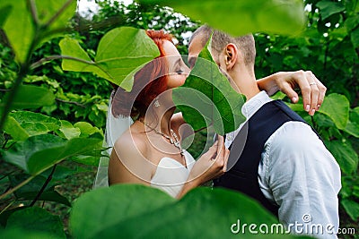 Newly wed couple snogging behind the bush in the park Stock Photo