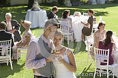 Newlywed Couple Toasting Champagne In Garden Stock Photo