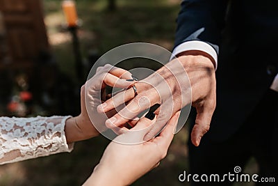 Newlyweds exchange rings against the backdrop of greenery Stock Photo