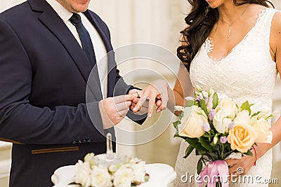 Newlyweds exchange rings, groom puts the ring on the bride`s hand Stock Photo