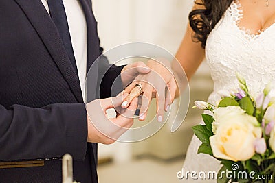 Newlyweds exchange rings, groom puts the ring on the bride`s hand Stock Photo