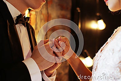 Newlyweds exchange rings, groom puts the ring on the bride`s hand in marriage registry office. Dark brown background Stock Photo