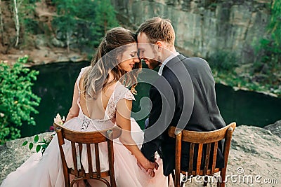 Newlyweds sitting at the edge of the canyon and couple looking each other with tenderness and love. Bride and groom Stock Photo