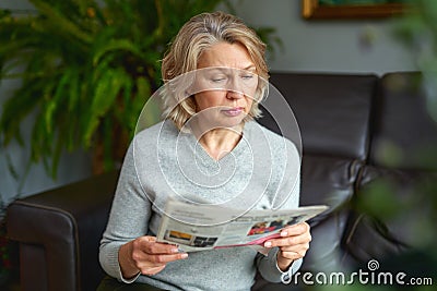 News, press, media, holidays and people concept - woman reading newspaper at home. Stock Photo