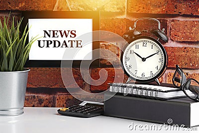 NEWS UPDATE text with alarm clock, books and vase on brick background Stock Photo