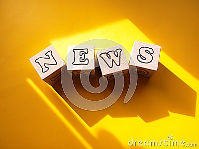 News - the word is written on wooden white cubes in the sunlight on a yellow background. Stock Photo