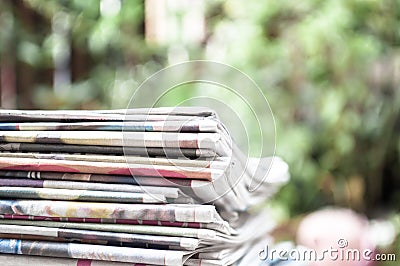 Newspapers folded and stacked on the table with garden or green background. Closeup newspaper and selective focus image. Time to r Stock Photo