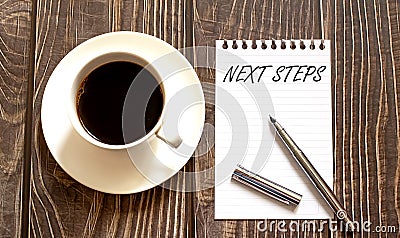 NEXT STEPS - white paper with pen and coffee on wooden background Stock Photo