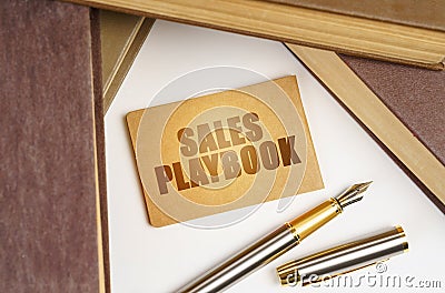 Next to the books lies a pen and a sign with the inscription - Sales playbook Stock Photo