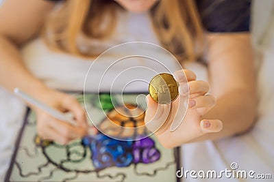 NFT Young woman, a digital artist, creates digital art on a tablet at home and shows a coin with the inscription NTF - Stock Photo