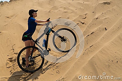 Girl with a bicycle climb the sand dunes Stock Photo