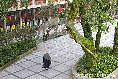 Ngong Ping, Lantau Island, Hong Kong - May 10, 2017. An anonymous view of a buddhist monk walking amongst beautiful gardens. Editorial Stock Photo