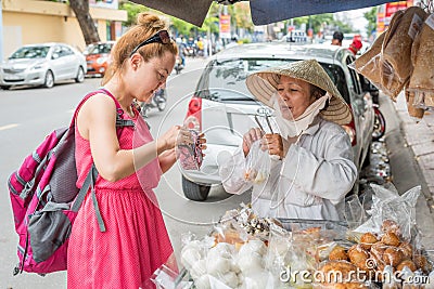 Nha Trang, Vietnam: A solo woman traveler buys sweets from a Vietnamese lady Editorial Stock Photo