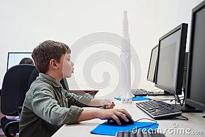 Nice caucasian concentrated boy using computer and the computer mouse Stock Photo