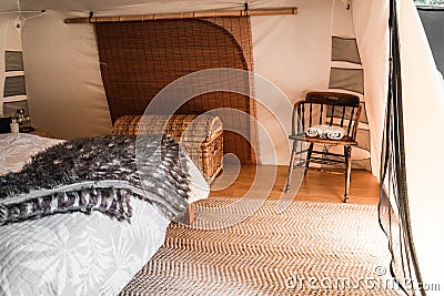 nice comfortable room in a tent with big wicker trunk and old wooden table with two rolled towels on it Stock Photo