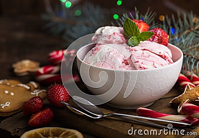 Ice cream served in a glass bowl. Displayed with candy canes on wooden rustic table. Sparkling Christmas tree lights background Stock Photo